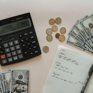 A calculator and some money on top of the table.