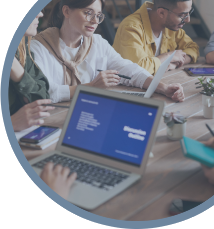 A group of people sitting around a table with laptops.