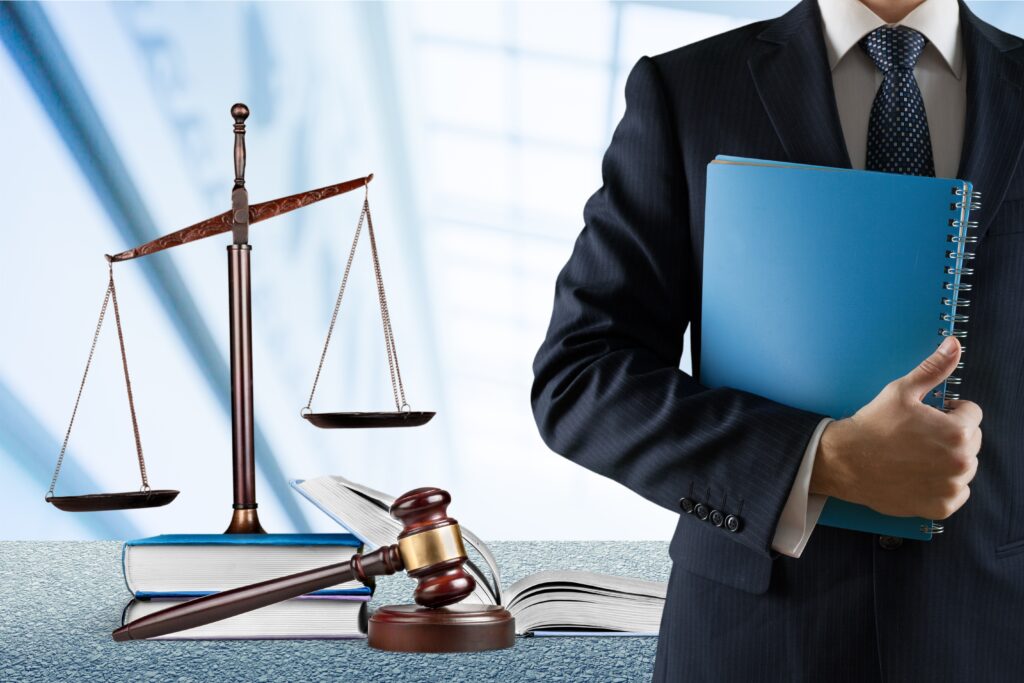 A person holding a blue folder in front of a gavel and scale.