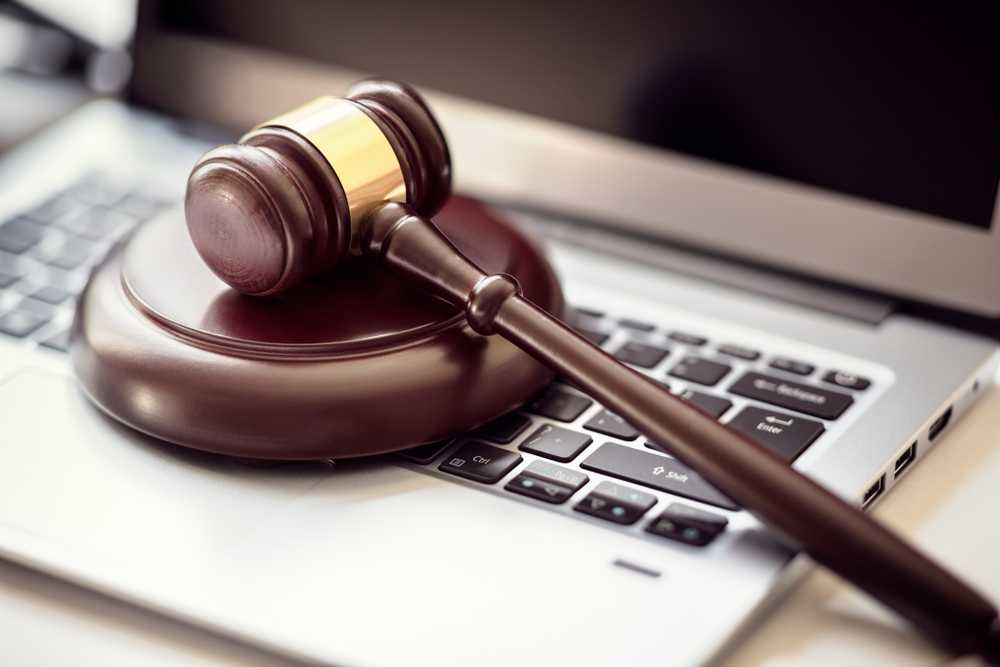 A wooden gavel sitting on top of a laptop.