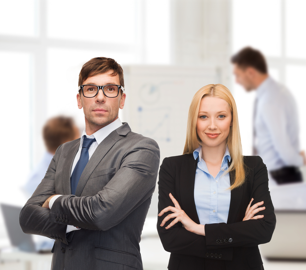 Two people standing in a room with their arms crossed.